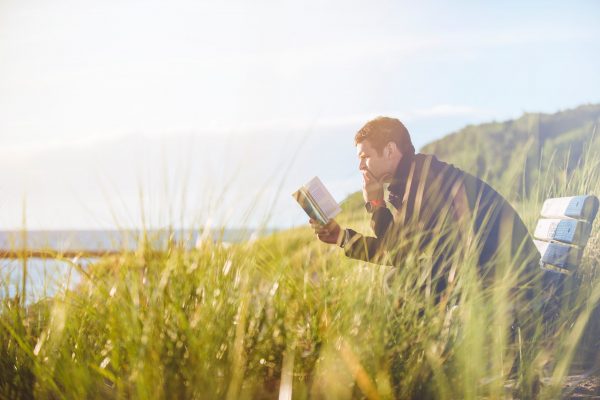 Un homme en train de lire un livre en pleine nature