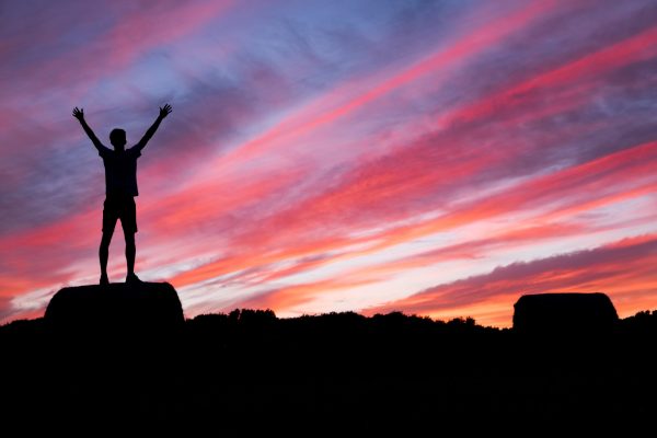 Homme levant les bras pendant un lever de soleil